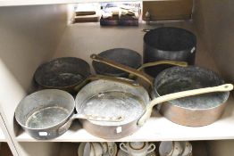 A group of five heavy brass-handled copper pans, and one copper pan without handle