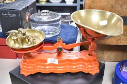 A pair of red-painted Libra Scale Company balance scales and six graduating brass bell weights