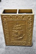 An embossed brass umbrella and stick stand with a galleon design and drip tray.