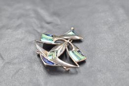 A silver brooch of stylised form having blue and green enamelled decoration, bearing marks to