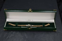 A 9ct gold bracelet having a central panther head panel with emerald and diamond chip decoration, on