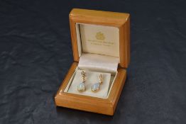 A pair of 9ct gold and opal drop earrings, having a shaped triangular section over the teardrop opal