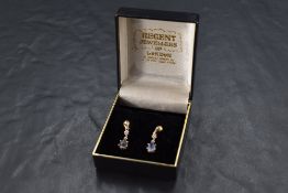 A pair of 9ct gold stud earrings having diamond chip set drops to pear cut powder blue sapphires,