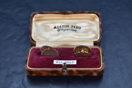 A cased pair of 9ct gold cufflinks of oval form having engine turned decoration and chain conectors,
