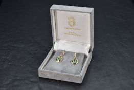 A pair of 14ct gold stud earrings having hinged drops with emerald and diamond chip decoration