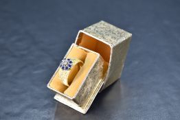 A powder blue sapphire and diamond cluster on a broad 18ct gold band having bark effect