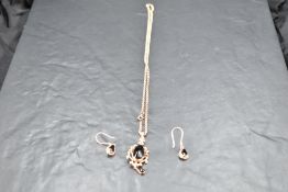 A 9ct rose gold jet pendant having a decorative open mount on a 9ct rose gold belcher chain, with