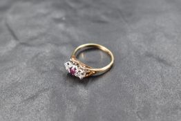 A ruby and diamond trilogy ring having a central ruby flanked by two small diamonds in illusionary