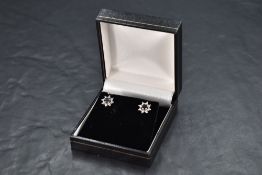 A pair of 18ct white gold sapphire and diamond chip star cluster earrings, approx 2.6g