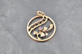 A small Edwardian yellow metal pendant stamped 9ct of circular form, having amethyst and seed