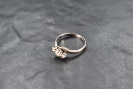 A diamond trilogy ring, total approx 0.35ct having cross over shoulders on a white metal loop