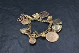 A 9ct gold double link charm bracelet having padlock clasp and twelve large charms including 1915