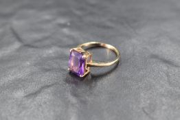 A baguette cut heat treated amethyst ring in a four claw setting on a 9ct gold loop, size R & approx