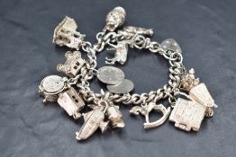 A silver charm bracelet having padlock clasp and sixteen white metal charms including stag, Romany