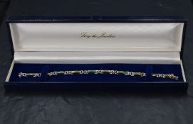 A white and yellow gold articulated bracelet stamped 14k having five panels set with black opal