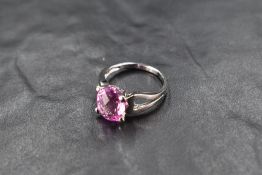 A facet cut pink topaz ring of oval form having four claw mount to open shoulders on a 9ct white