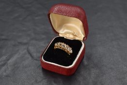 A five stone graduated brilliant cut diamond ring having eight diamond chip spacers in a scrolled