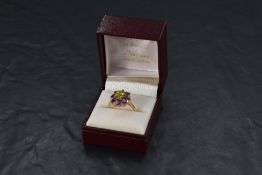 A large amethyst and diamond chip oval cluster ring with central green gem in a stepped claw set