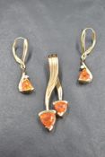 A yellow metal pendant with matching earrings, all stamped 14K having trillion cut fire opals, the