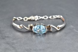 A silver bracelet having a large central blue topaz