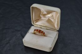 A five stone graduated fire opal ring in a gallery mount with scroll decoration on a 9ct gold
