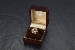 A garnet & seed pearl cushion cluster ring having split shoulders on a 9ct gold loop, size N/O &