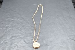 A yellow metal locket of circular form having engraved decoration on a rose gold chain bearing 9ct