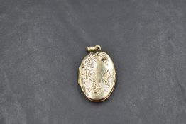 A 9ct gold oval locket having white gold and engraved floral decoration to front, approx 4.6g