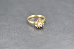 A diamond solitaire ring, approx 0.125ct in a 4 claw set stylised star burst mount on an 18ct gold