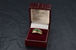 An Emerald and diamond set band ring having seven central princess cut emeralds, total approx 1ct,