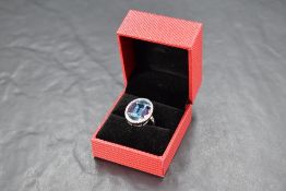 A blue topaz and amethyst ring having five stones set as an oval panel within a diamond chip