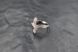 A diamond chip set vertical knot twist ring having diamond chip set shoulders on an 18ct white