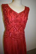 A 1950s 'Suzanne, Bradford' red organdie evening dress, having full concertina pleated skirt with b
