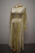 An early 1950s cream patterned wedding dress having full length sleeves, full skirt and rear metal