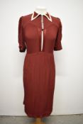 An Art Deco day dress of burgundy crepe, having collar with contrasting edge, buttons to bodice,
