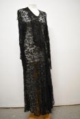 A black lace 1930s dress, having full length sleeves gathering into a pointed cuff and sash detail
