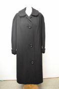 A late 1950s black wool coat having Astrakhan collar and cuffs and Dereta label, larger size.