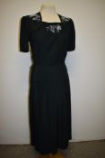 A 1940s day dress having piping to bodice and white beadwork, side metal zip and single button to