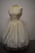 A 1950s cream dress, having patterned sheer layer over taffeta lining, full skirt, Peter pan