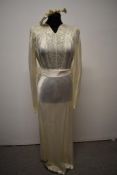 A 1930s ivory satin wedding dress having smocking and braid work to bodice, full length sleeves, tie