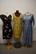 Three vintage 1950s to early 1960s dresses, including oriental style black satin dress with yellow