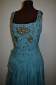 A 1950s evening gown in sky blue, having beading and sequins to front, oversized bow to hip of very