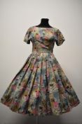 A 1950s cotton day dress having full pleated skirt and novelty abstract print in pink, blue,