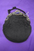 A stunning early 20th century black quilted bag, having semi precious stones to filigree frame.
