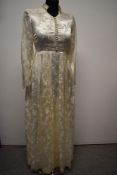 A late 1940s/ early 1950s wedding dress in patterned ivory satin, having pleated skirt, long sleeves