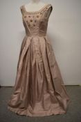A 1950s ball gown of taupe shot satin or similar, having extensive beading, metal thread accents and