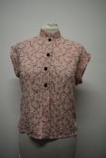 A pale pink 1950s blouse, having machine embroidered floral pattern in black with black buttons,