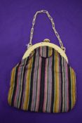 An early 20th century striped bag, having early plastic frame and strap and cerise pink silk lining,