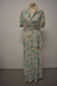 A late 1940s/50s seersucker cotton housecoat, having green and pink rose pattern with pink piping to