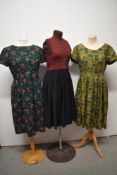 Three vintage dresses, to include bottle green dress with rose print, around 1960s, red and black